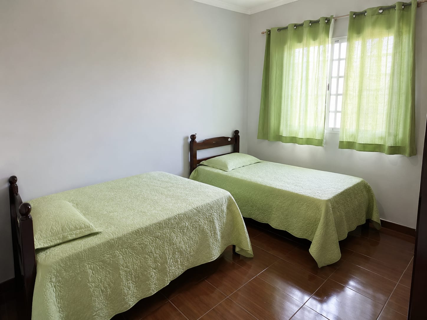 Quarto arejado com duas camas e detalhes verdes